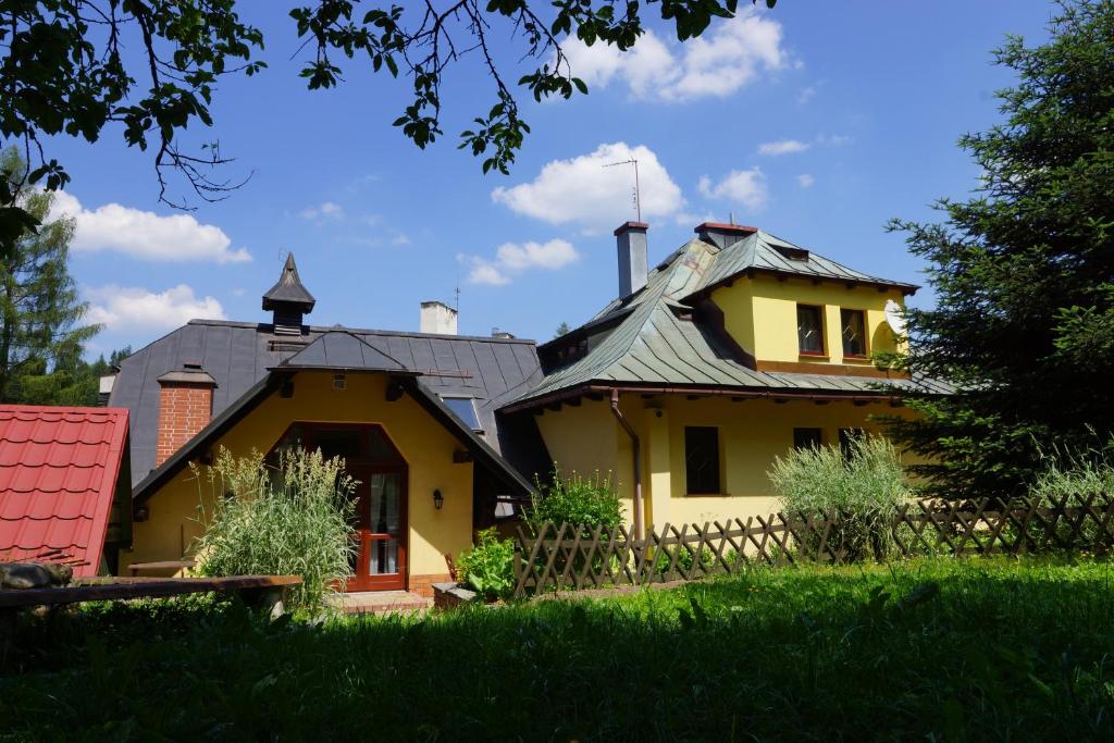 una casa amarilla con techo de metal en un patio en Villa Goździk, en Wisła