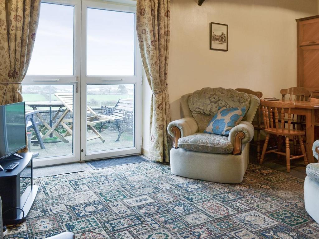 ein Wohnzimmer mit einem Stuhl und einer Glasschiebetür in der Unterkunft The Cottage Gallt Y Balch in Bodorgan