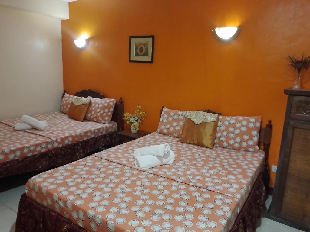 2 camas en una habitación con paredes de color naranja en Lucky Garden Inn, en Puerto Princesa City