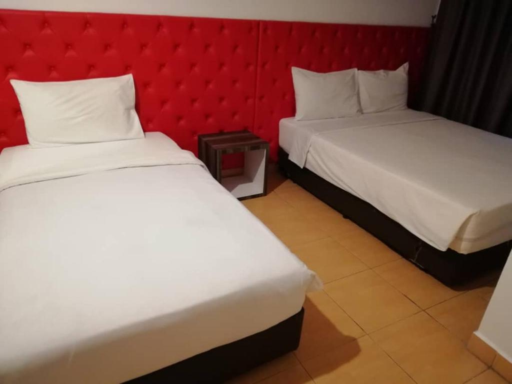 Habitación de hotel con 2 camas y pared roja en SUNTEC HOTEL, en Johor Bahru