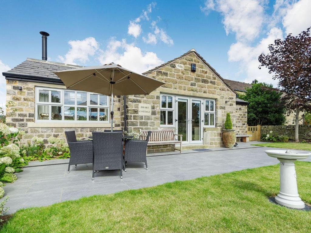 une terrasse avec une table, des chaises et un parasol dans l'établissement Drake Cottage, à Wilsden