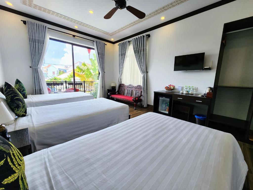 a hotel room with two beds and a flat screen tv at Vincent's House in Hoi An