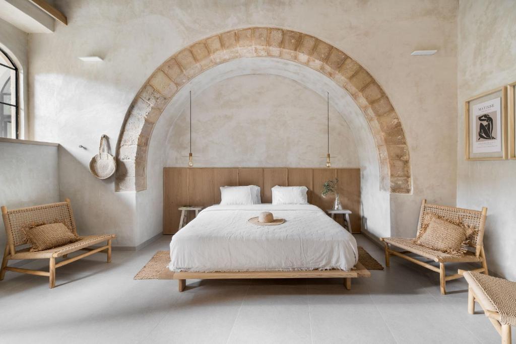 a bedroom with a large bed and two chairs at Melisende in ‘Akko