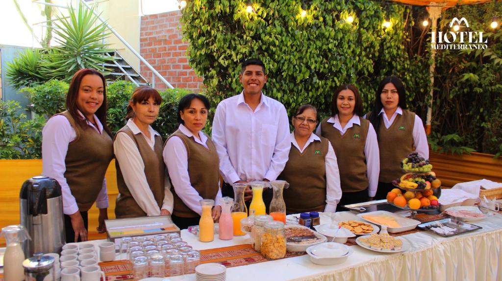 a group of people standing next to a table with food at Hotel Mediterraneo Arequipa in Arequipa