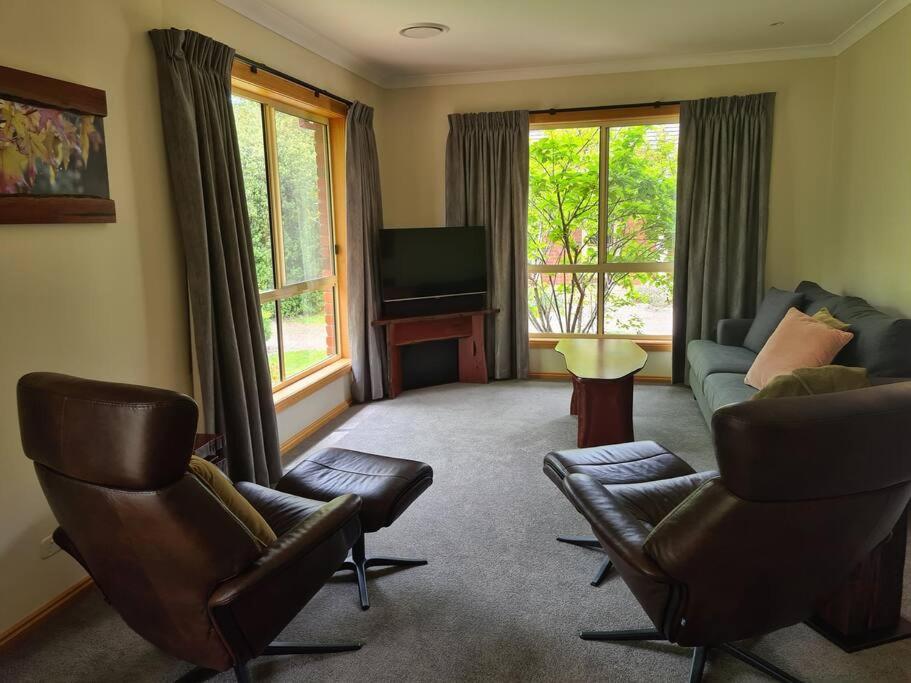 a living room with a couch and chairs and a tv at REDGUM RETREAT BRIGHT - Luxury Spa Villa in Bright