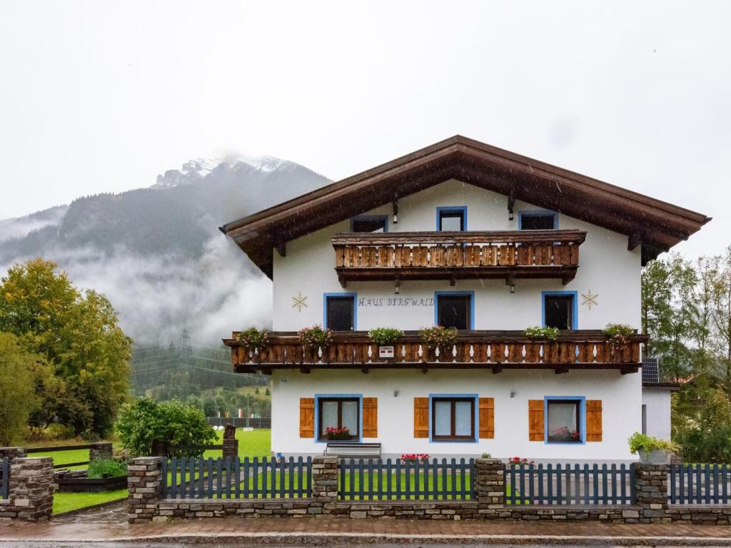 ein weißes Haus mit einem Balkon und Bergen im Hintergrund in der Unterkunft Apartment in Bichlbach with a shared sauna in Bichlbach