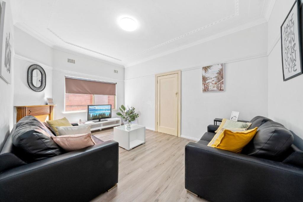 a living room with two black leather couches and a television at Burwood Newly Renovated 2 Bedroom Apartment in Sydney