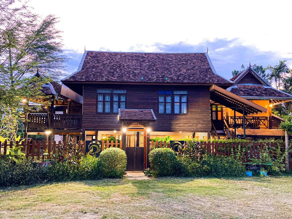 ein großes Holzhaus mit Lichtern an der Vorderseite in der Unterkunft Chiangmai Lanna in San Kamphaeng