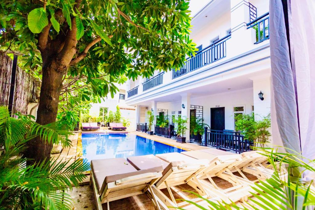 einen Pool mit Chaiselongues neben einem Gebäude in der Unterkunft Rithy Rine Angkor Residence in Siem Reap