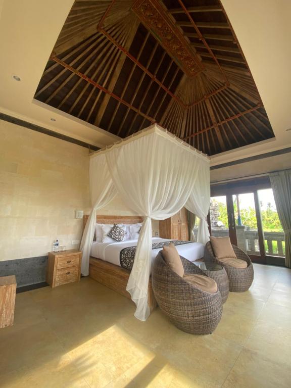 a bedroom with a bed with a canopy and chairs at Anggarakasih Ubud Villa in Ubud