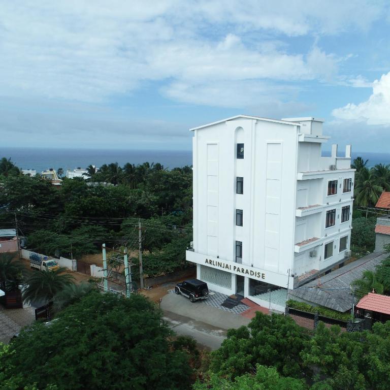 a white building with the ocean in the background at Arlinjai Paradise in Kanyakumari