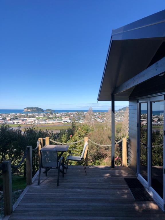 a wooden deck with a table and chairs on it at Mandhari - The View in Whangamata