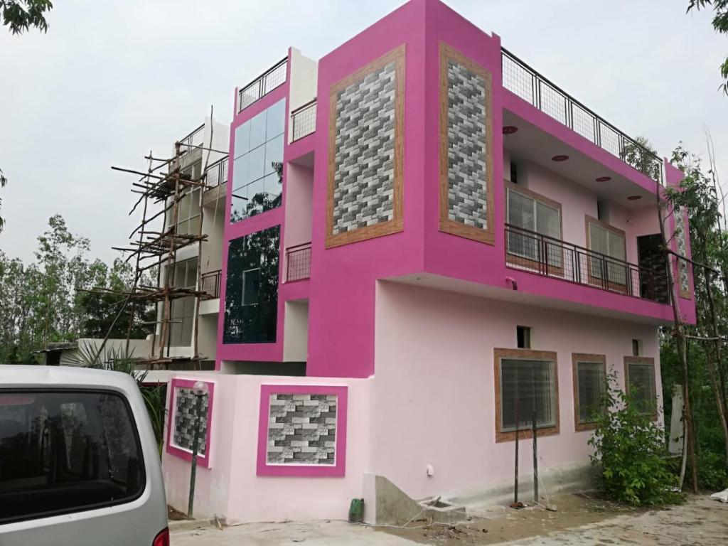 a pink building with a car parked in front of it at Panna Tiger Home Stay in Khajurāho