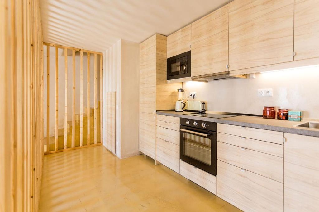 a kitchen with wooden cabinets and a stove top oven at Sea'Ya Thoughtful Stays - Villas in Cascais