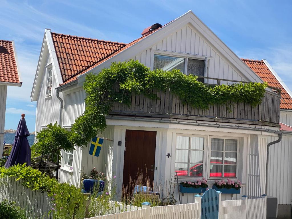 a white house with a fence in front of it at Bekvämt boende mitt i gamla genuina Skärhamn in Skärhamn