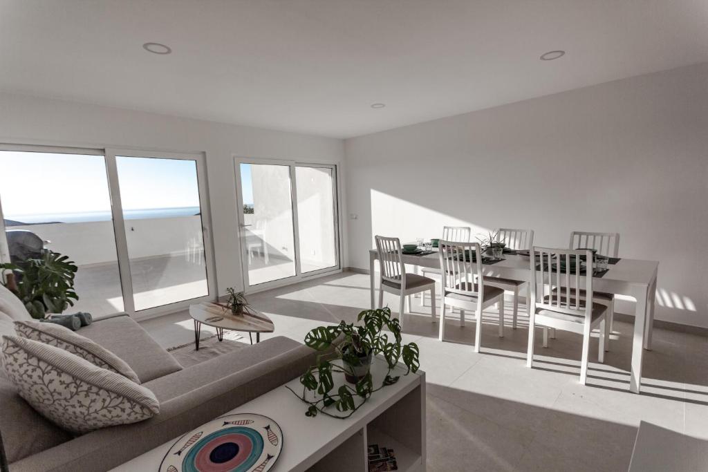 un soggiorno con un divano, un tavolo e delle sedie di Arrifana Sunset Sea View Villa a Praia da Arrifana