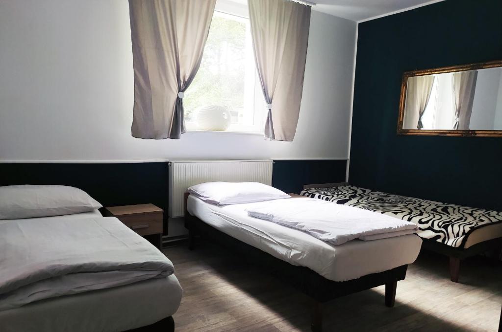 a bedroom with two beds and a window and a mirror at Pokoje gościnne na Miłej in Kochlice