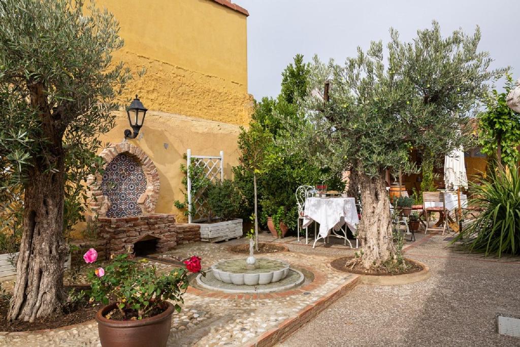 een tuin met bomen en een tafel en een fontein bij Beautiful Alamedas: casa rural con piscina in Castronuño