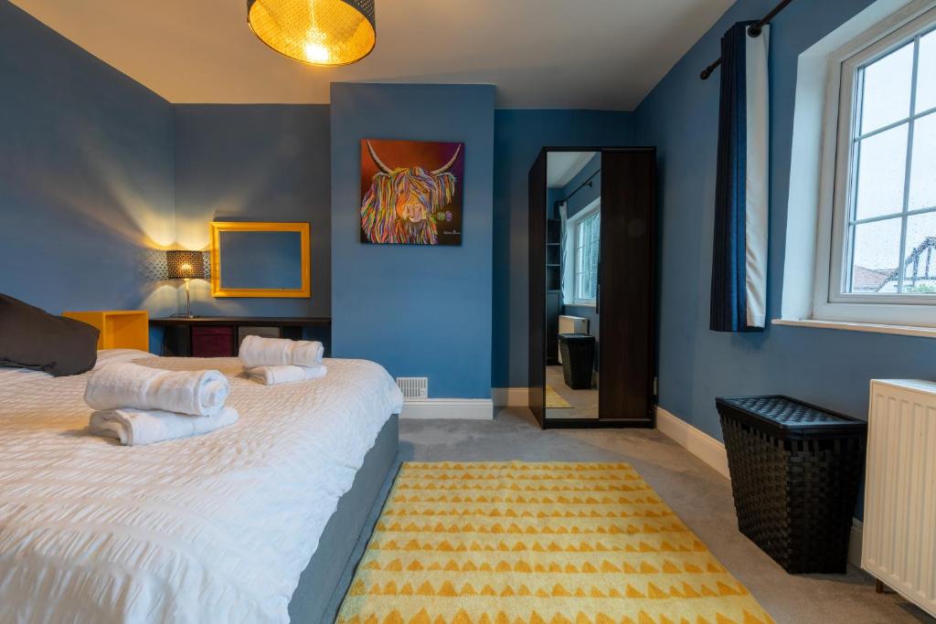 um quarto com paredes azuis e uma cama com almofadas brancas em 3 bedroom home and garden in North Bristol em Bristol