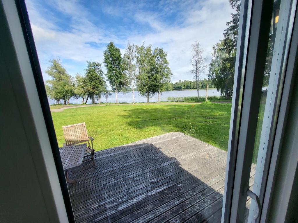una ventana con vistas a una terraza con un banco en Mökki Vanajaveden rannalla Kirstulan Kartanossa, en Hämeenlinna