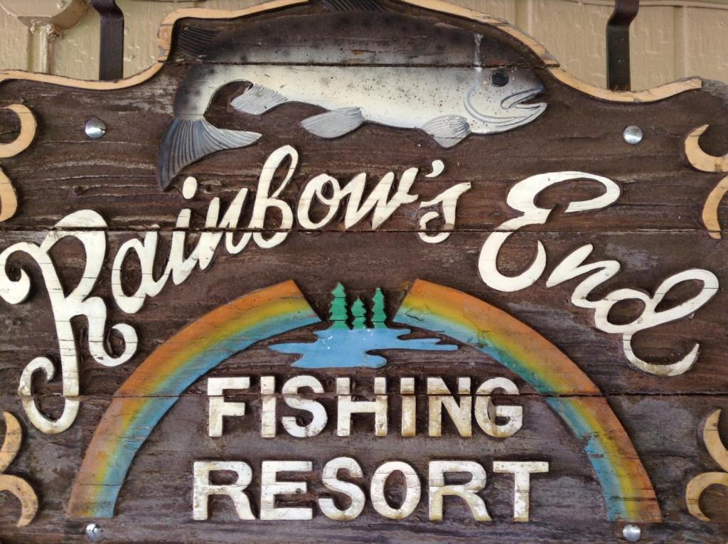 ein Schild mit einem Regenbogen und einem Schild für ein Forellenangelgebiet in der Unterkunft Rainbows End Fishing Resort in Pinetop-Lakeside