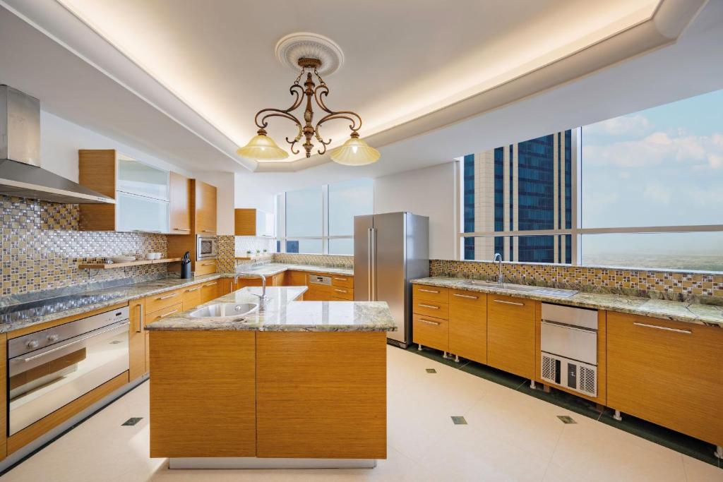 a large kitchen with wooden cabinets and a large window at Dusit Hotel & Suites - Doha in Doha