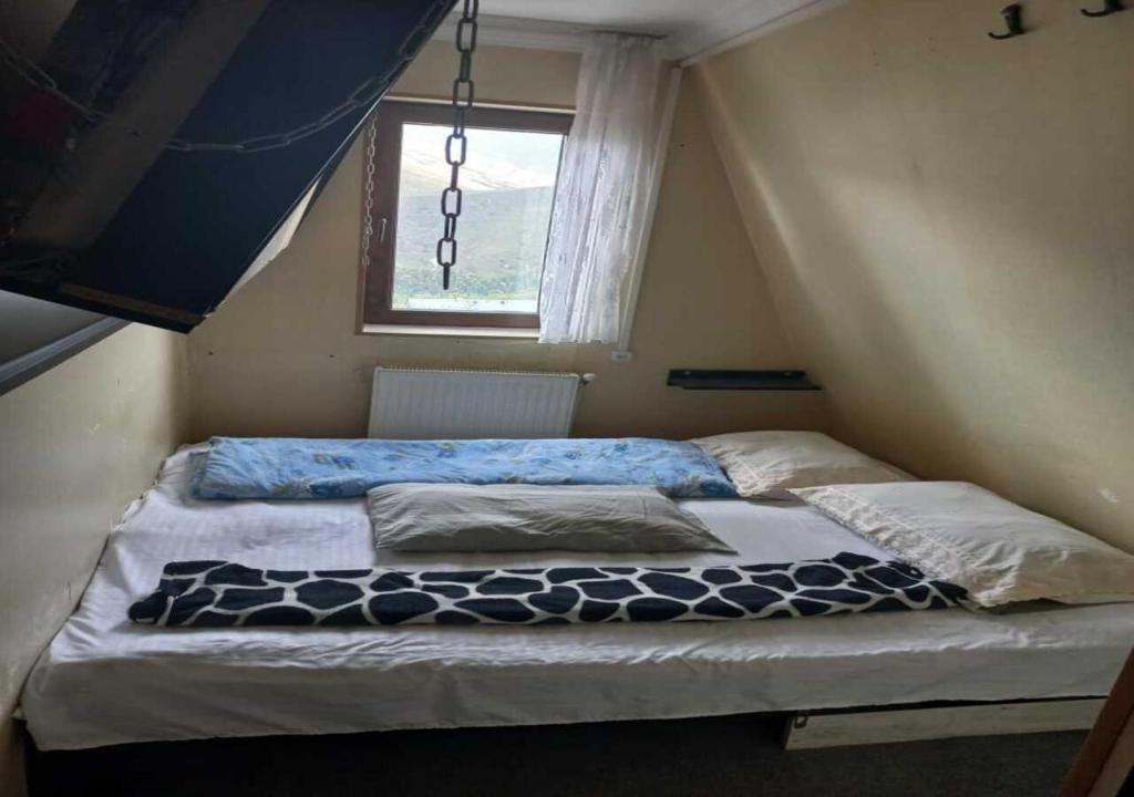 Bett in einem kleinen Zimmer mit Fenster in der Unterkunft Taj Hostel in Gudauri