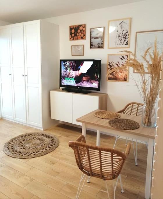 - un salon avec une télévision, une table et des chaises dans l'établissement Boho apartament - studio, à Kołobrzeg