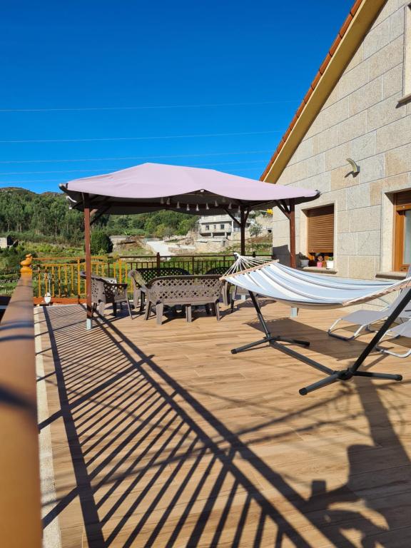 a deck with two hammocks and a large umbrella at A Veiga Grande in Pontevedra