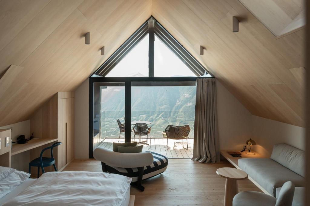 a bedroom with a large window in a attic at Miramonti Boutique Hotel in Avelengo