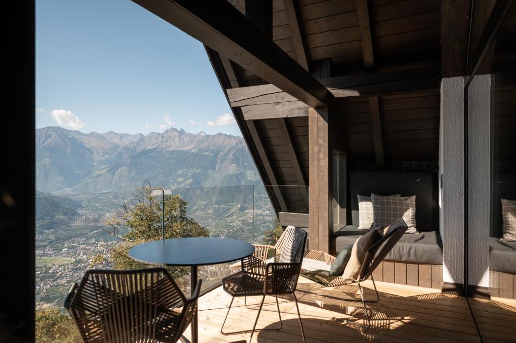 a balcony with a table and chairs and mountains at Miramonti Boutique Hotel in Avelengo