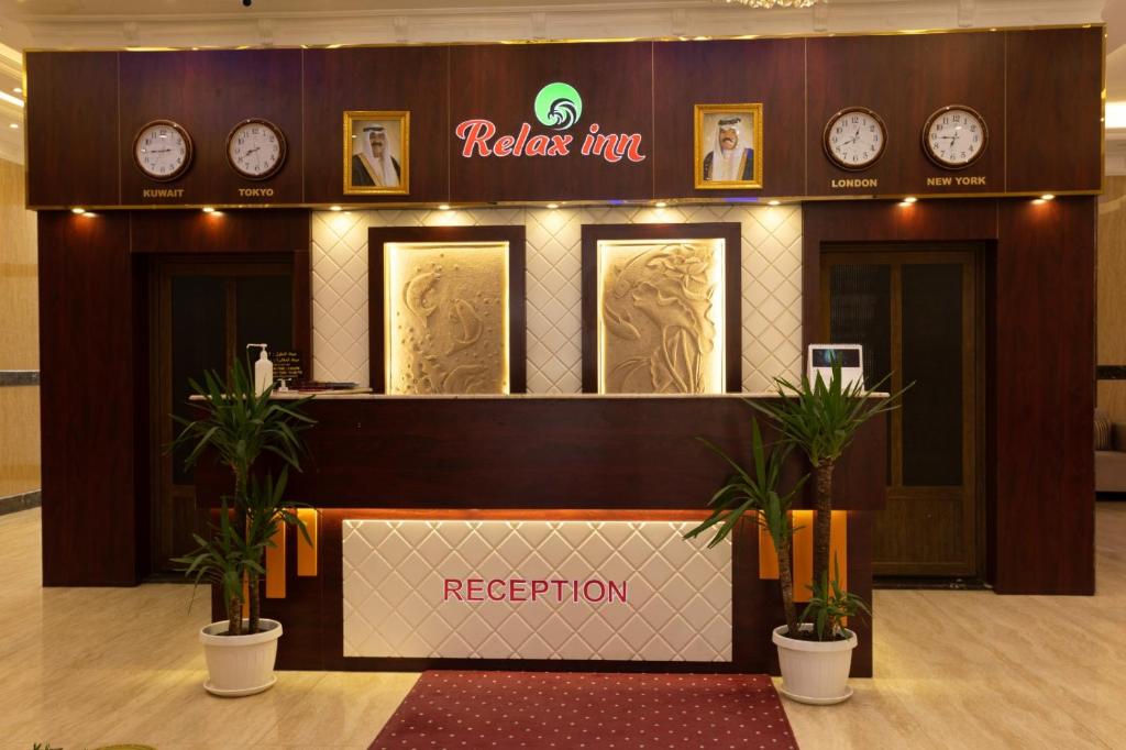 um lobby do hotel com relógios na parede e uma recepção em Relax inn Apartment - Fahaheel em Kuwait