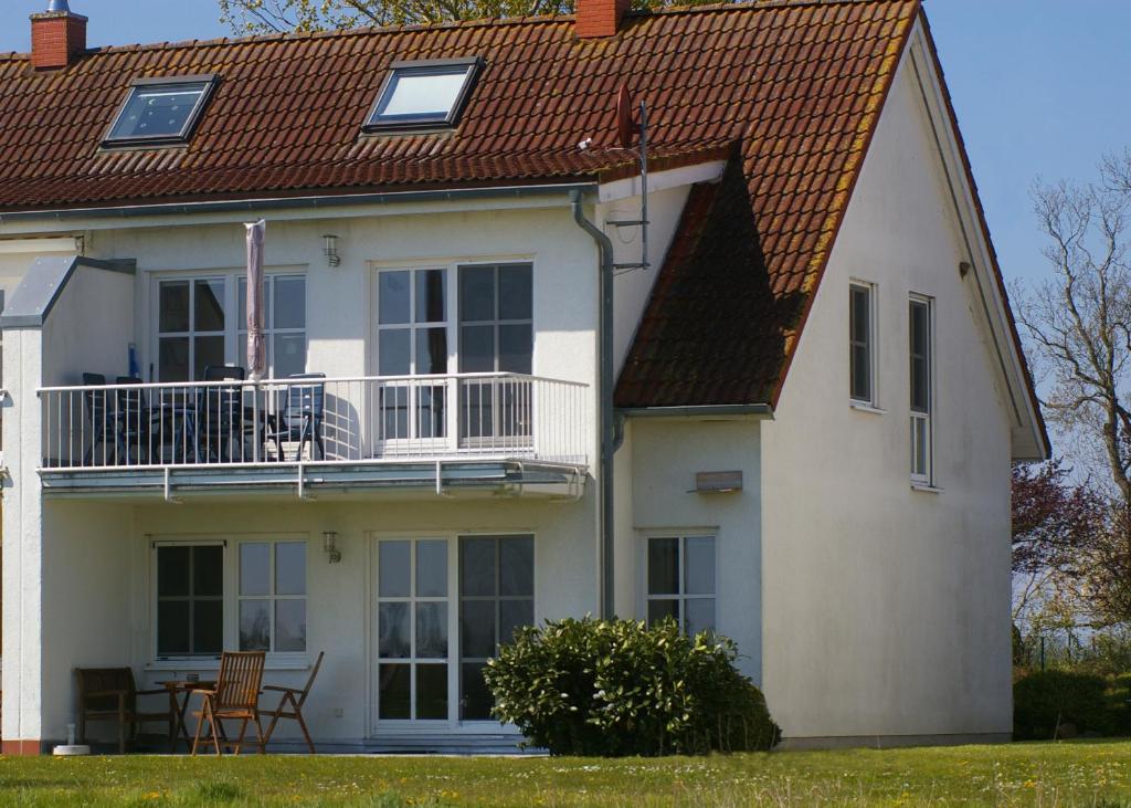 a white house with a deck and a balcony at Ferienwohnung Schwalbennest in Zudar