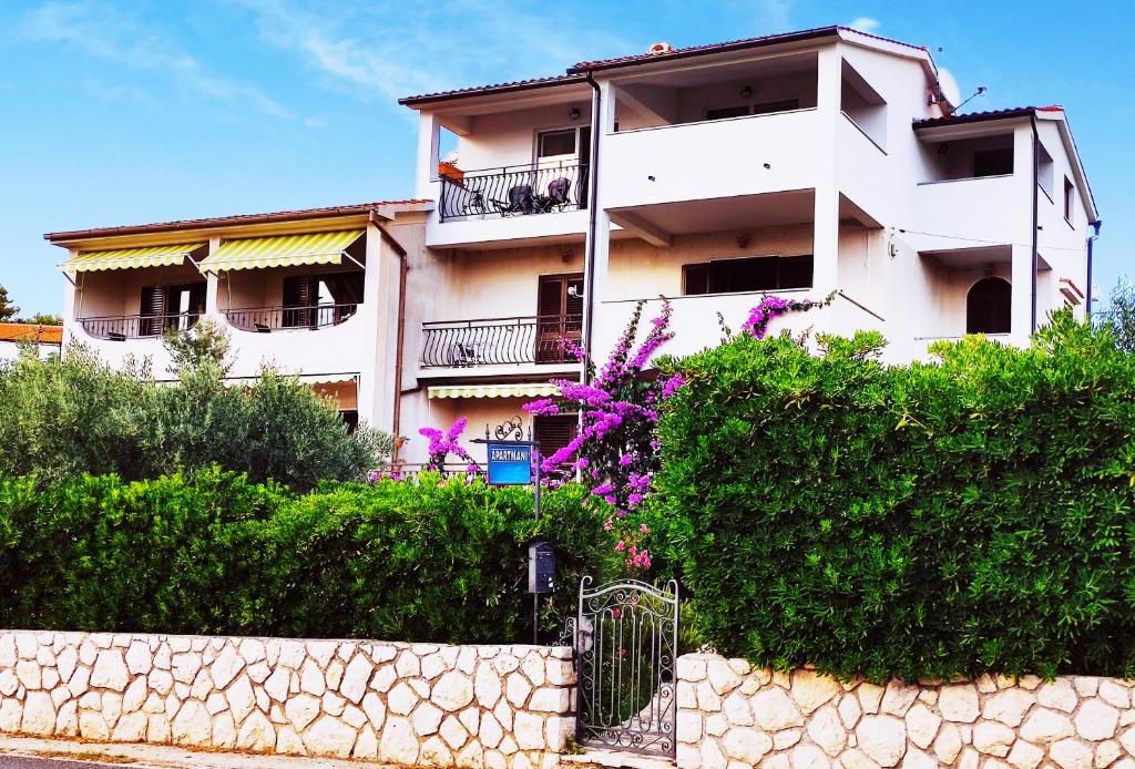 a white building with a fence in front of it at Villa Jadranka in Rab