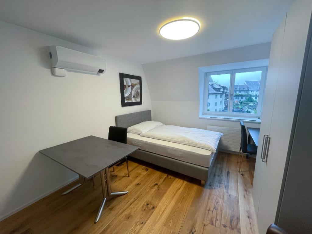 um pequeno quarto com uma cama e uma mesa em SCHNYDER'S HOME - Studio_1 em Rapperswil-Jona