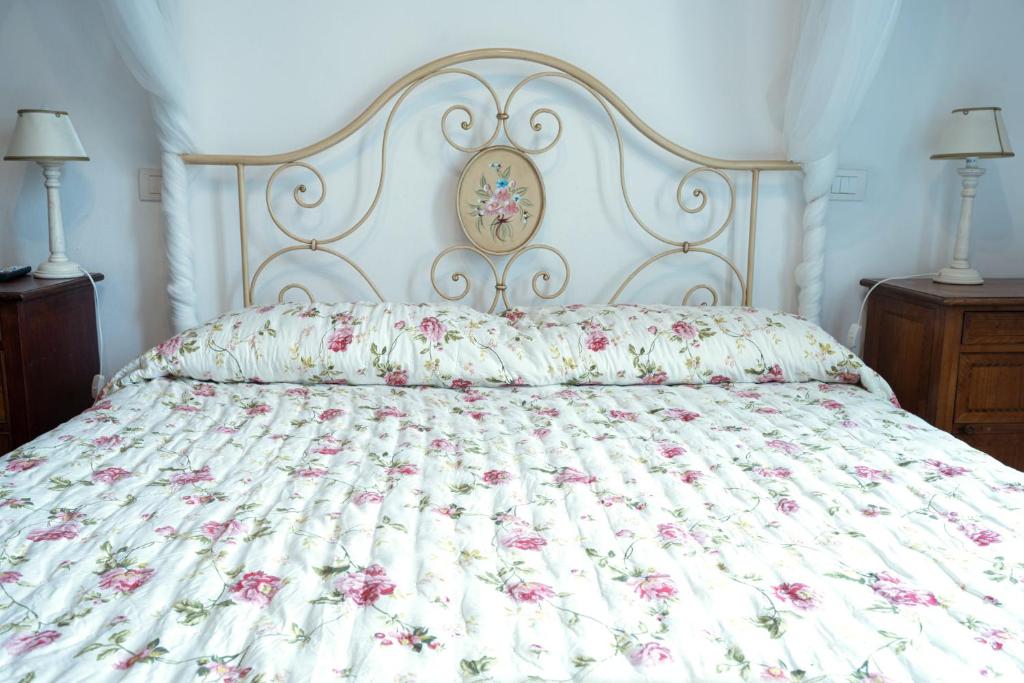 un letto con copriletto floreale e 2 lampade; di Affittacamere Le camerine di Silvia 2 a Siena
