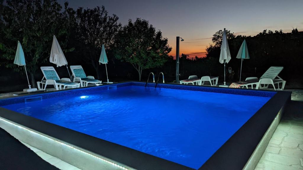 ein großer blauer Pool mit Stühlen und Sonnenschirmen in der Unterkunft Apartman Aja in Kaštelir