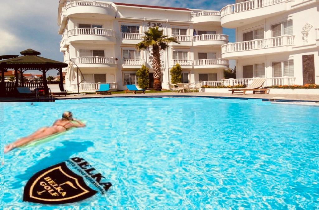 a person swimming in a swimming pool in front of a building at Belka Golf Residence Delux apt Poolside in Belek