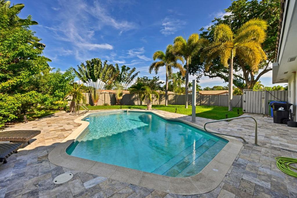 a swimming pool in a yard with palm trees at Moana Beach Cottage in Fort Lauderdale