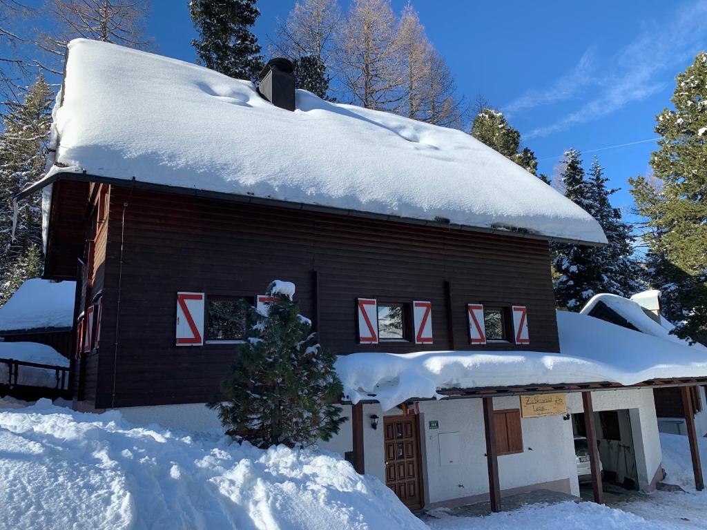a house covered in snow with a christmas tree in front at Zirbenwald Lodge in Turracher Hohe