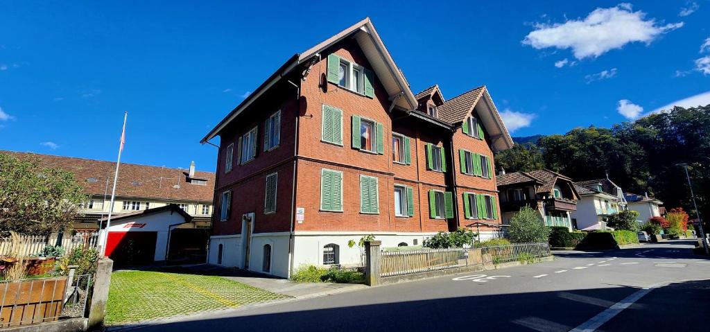 un grand bâtiment en briques avec volets verts dans une rue dans l'établissement New West Station, à Interlaken