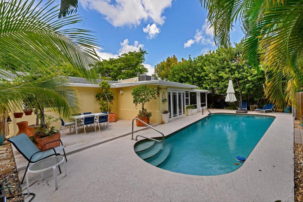 a swimming pool with chairs and a house at Cinderella's Beach Cottage in North Palm Beach