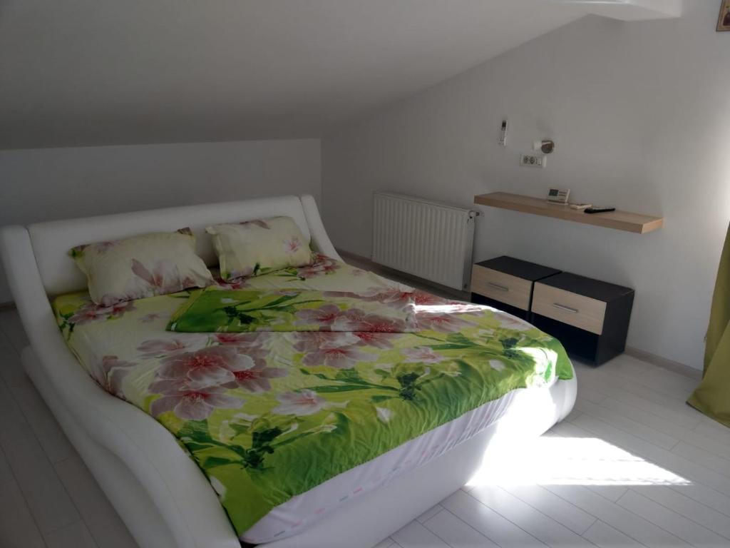 a bedroom with a bed with a floral bedspread at Fun Apartament Militari Residence in Roşu
