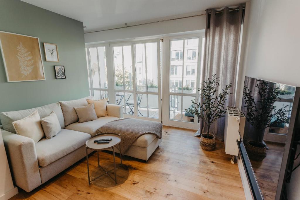 salon z kanapą i dużym oknem w obiekcie Stylisches Apartment im Herzen Leipzigs mit Balkon w Lipsku