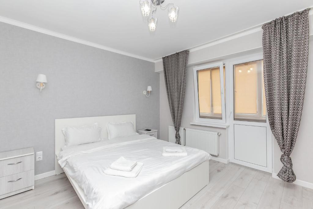 um quarto branco com uma cama branca e uma janela em Apartament in zona Centrala si Parc em Chisinau