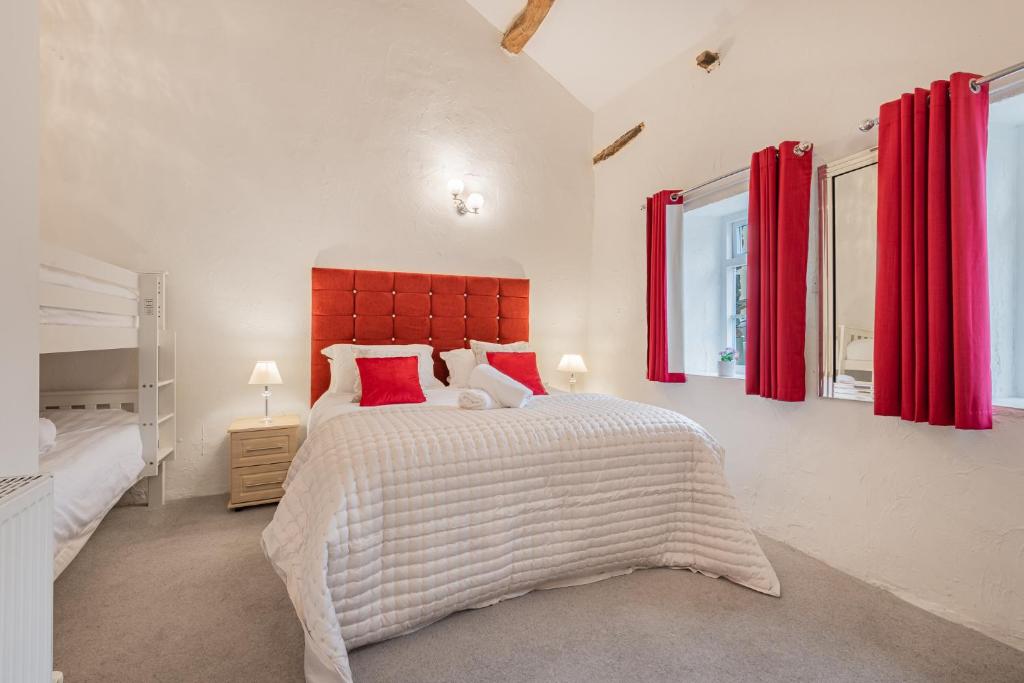 a bedroom with a large bed and two windows at Cottage 3 Old Farmhouse Mews in Keswick
