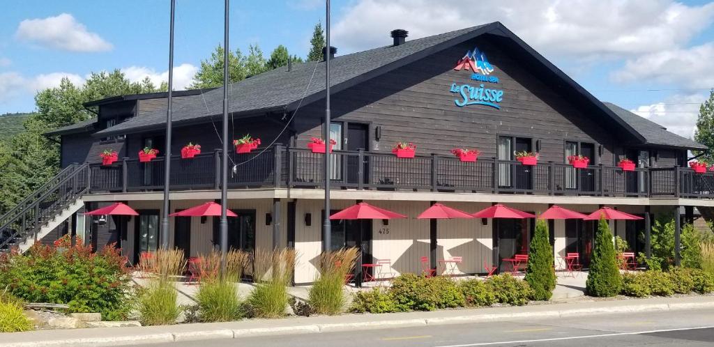 un bâtiment avec un restaurant doté de parasols rouges dans l'établissement Hotel "Le Suisse", à Saint-Donat-de-Montcalm