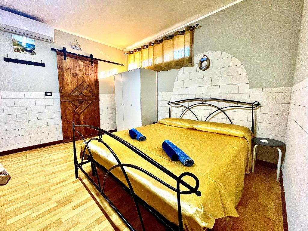 Cette chambre comprend un lit avec des draps jaunes et du parquet. dans l'établissement Monolocale Deluxe a 2,7 km dal mare per 2 persone, à Siderno Marina
