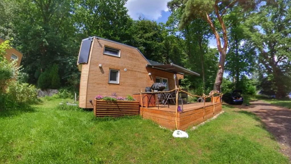 a tiny house with a deck in a yard at Ferien im Tiny House in Stuer