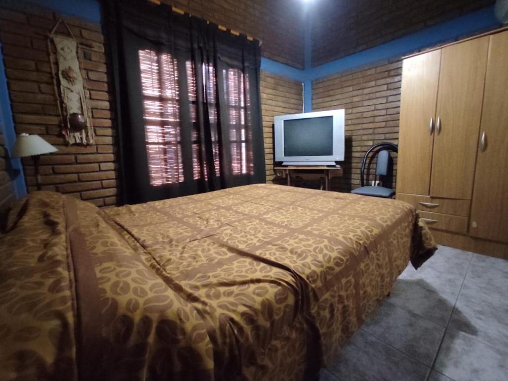 um quarto com uma cama e uma televisão de ecrã plano em Dpto Alma en Calma San Rafael em São Rafael